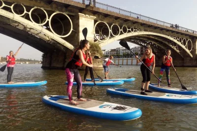 Erlebe sevilla vom guadalquivir aus beim paddle surf, gleite unter der triana-brücke vorbei, mit lokalem guide, getränken in triana und einem video als erinnerung.