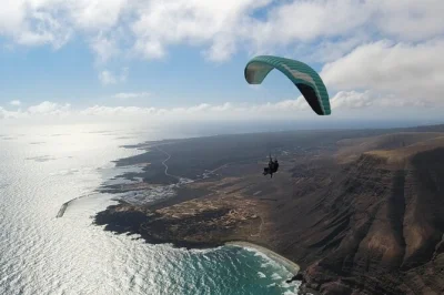 Erlebe lanzarotes lavafelder und atlantikküste aus der luft bei einem tandem-paragliding mit erfahrenem schweizer piloten. inklusive ausrüstung & abholung.