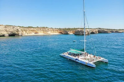 Feel the breeze on a catamaran cruise along benagil cave, carvoeiro, and praia da rocha. swim, try sup, and relax with onboard water activities. includes all fees.