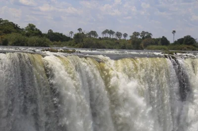 Feel the spray from victoria falls on a guided day trip across zimbabwe & zambia, with hotel pickup and live guides. includes raincoats and time at a local market.