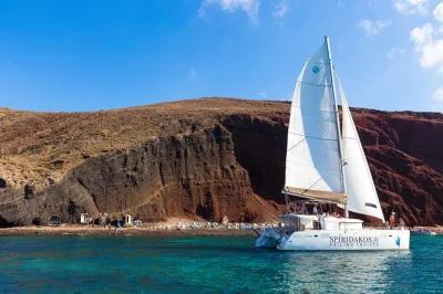 Feel the breeze on a santorini catamaran cruise—swim at red & white beach, soak in volcanic springs, and enjoy bbq lunch with wine. includes hotel transfers.
