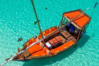 Navega en dhow desde zanzíbar a isla mnemba, nada con delfines, explora arrecifes de coral y disfruta un bbq de mariscos fresco con bebidas y equipo de snorkel incluido.