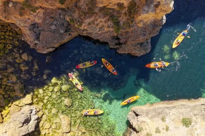 Descubra a costa do algarve de perto com um passeio de caiaque saindo de lagos até as grutas da ponta da piedade, com apoio de catamarã, tempo para nadar e guia local experiente.