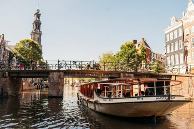 Step onto a classic saloon boat for a 1-hour amsterdam canal cruise with live guide, heated cabin, drinks for purchase, and city stories. includes pickup nearby.