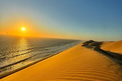 Coucher de soleil à Sandwich Harbour : Dunes et mer à l'heure dorée